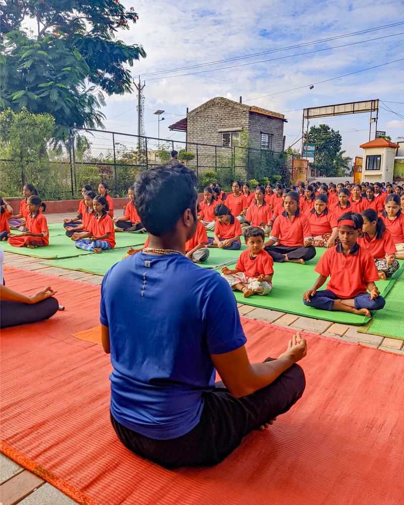Prathamesh Chavan leading a large outdoor group in seated meditation